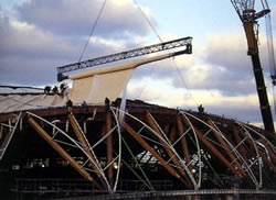 A crane assists in unrolling of membrane near top of
